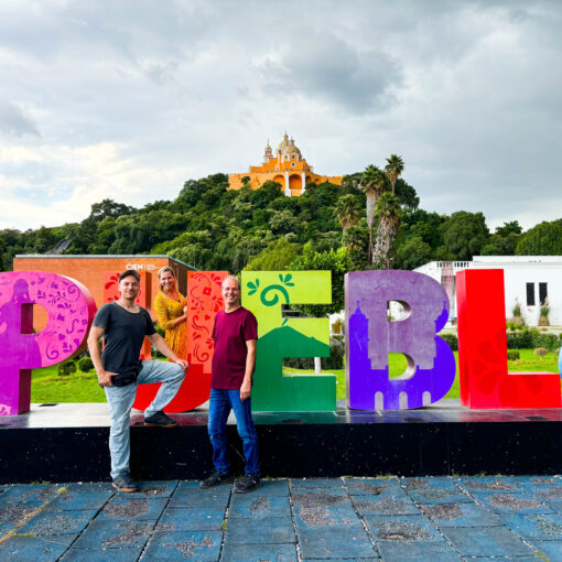 drei Personen vor Schild Puebla und Berg im Hintergrund