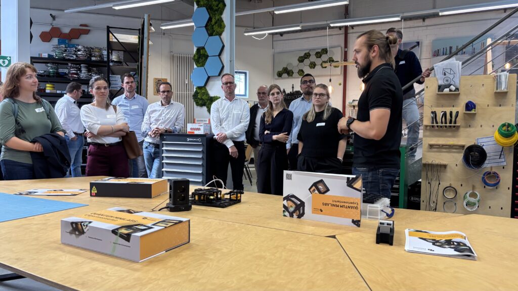 Besuchergruppe im Hintergrund, im Vordergrund Quantum Minilabs Kits.